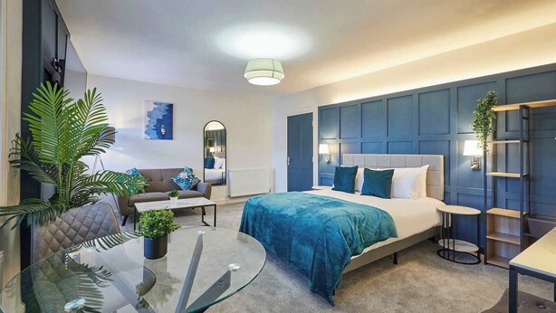A modern hotel room with a large bed, a glass coffee table, a sofa, and a desk. - Host & Stay | The Langley Hotel, Apartment 8 (Whitby)