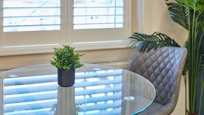 A glass table with a potted plant, a chair, and a window with blinds. - Host & Stay | The Langley Hotel, Apartment 8 (Whitby)