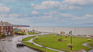 Eine Küstenstraße mit Kreisverkehr, Grünflächen und Blick aufs Meer.