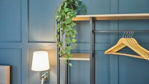 Un muro con una pianta sospesa, una gruccia di legno e una lampada a parete.
