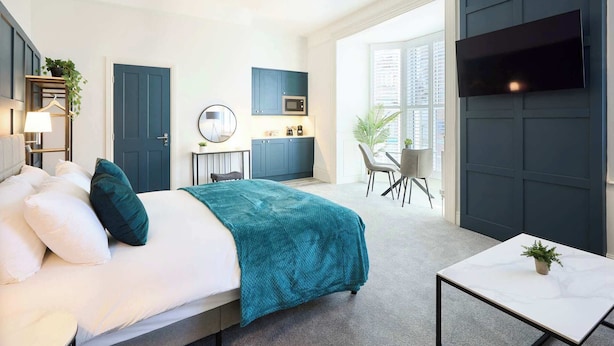 Una camera d'albergo moderna con un letto, un comodino, una scrivania e una televisione.
