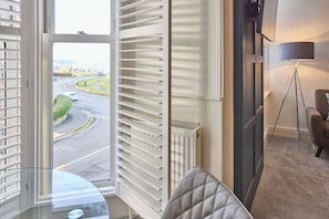 Ein Hotelzimmer mit großem Fenster, Heizkörper, Fernseher und Lampe.