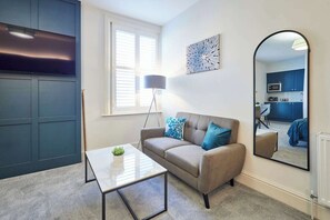 A modern living room with a sofa, a coffee table, a floor lamp, and a large mirror. - Host & Stay | The Langley Hotel, Apartment 6 (Whitby)