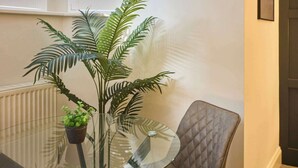 Ein Tisch mit Glasplatte, darauf ein Blumentopf und eine kleine grüne Pflanze.