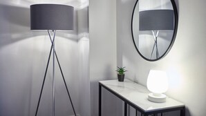 Ein modernes Zimmer mit Stehlampe, Tisch mit Lampe und Spiegel an der Wand.