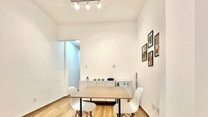 Ein modernes, minimalistisches Zimmer mit einem Holzespeisetisch und weißen Stühlen, einer kleinen Küchenzeile und einer hellblauen Akzentwand.