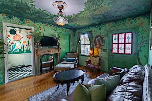 A room with a checkered floor, a sofa, a television, and a fireplace.