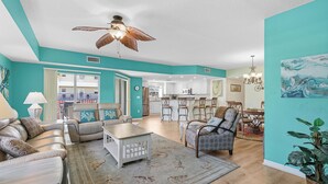 Ein geräumiges Wohnzimmer mit Deckenventilator, einem Essbereich und einer Küche im Hintergrund.