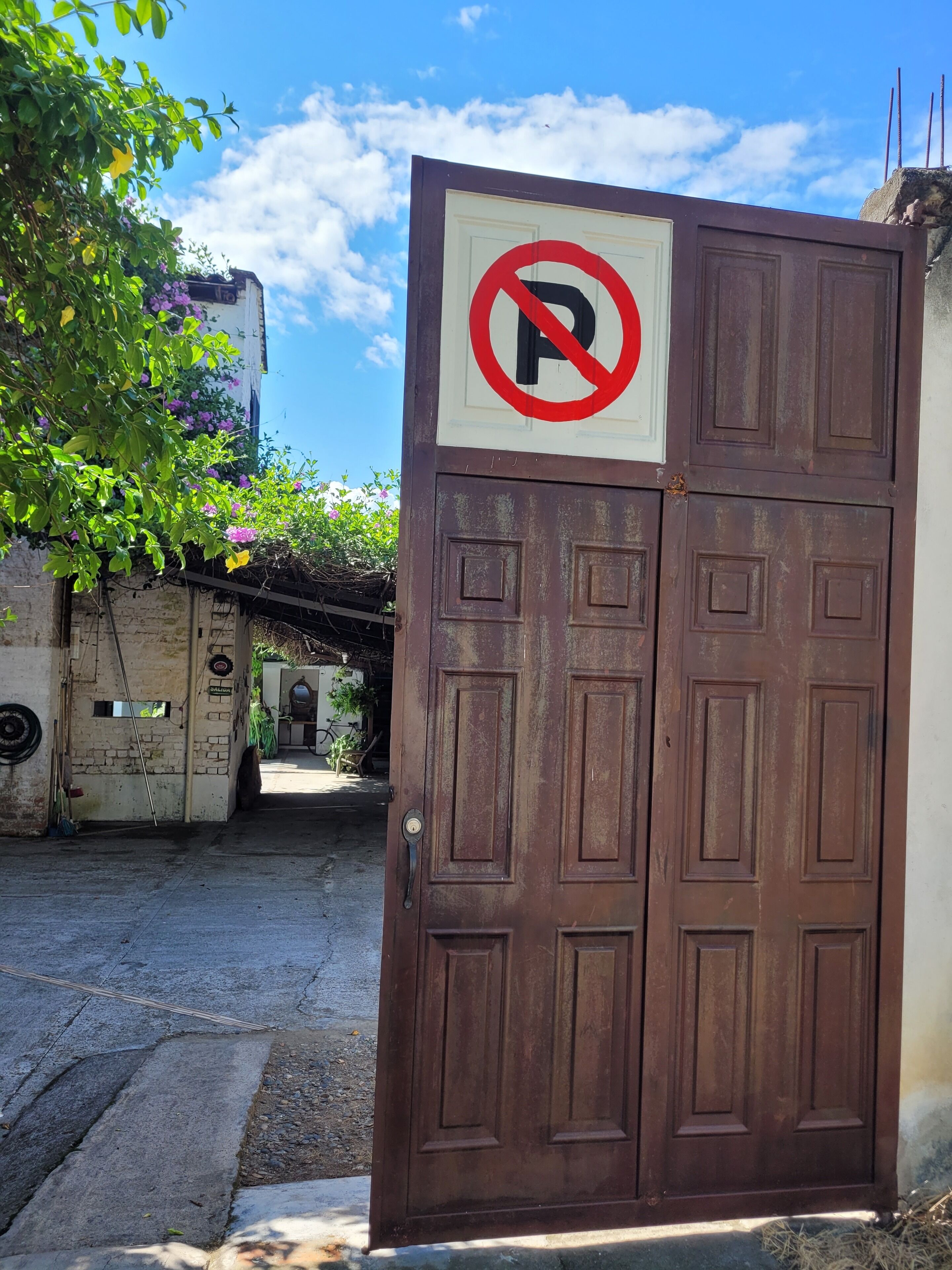 Una puerta marrón cerrada con un cartel de prohibido estacionar.