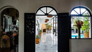Blick in die Hotelhalle mit gefliestem Boden, einer Rezeption und einem Blick auf den Poolbereich.