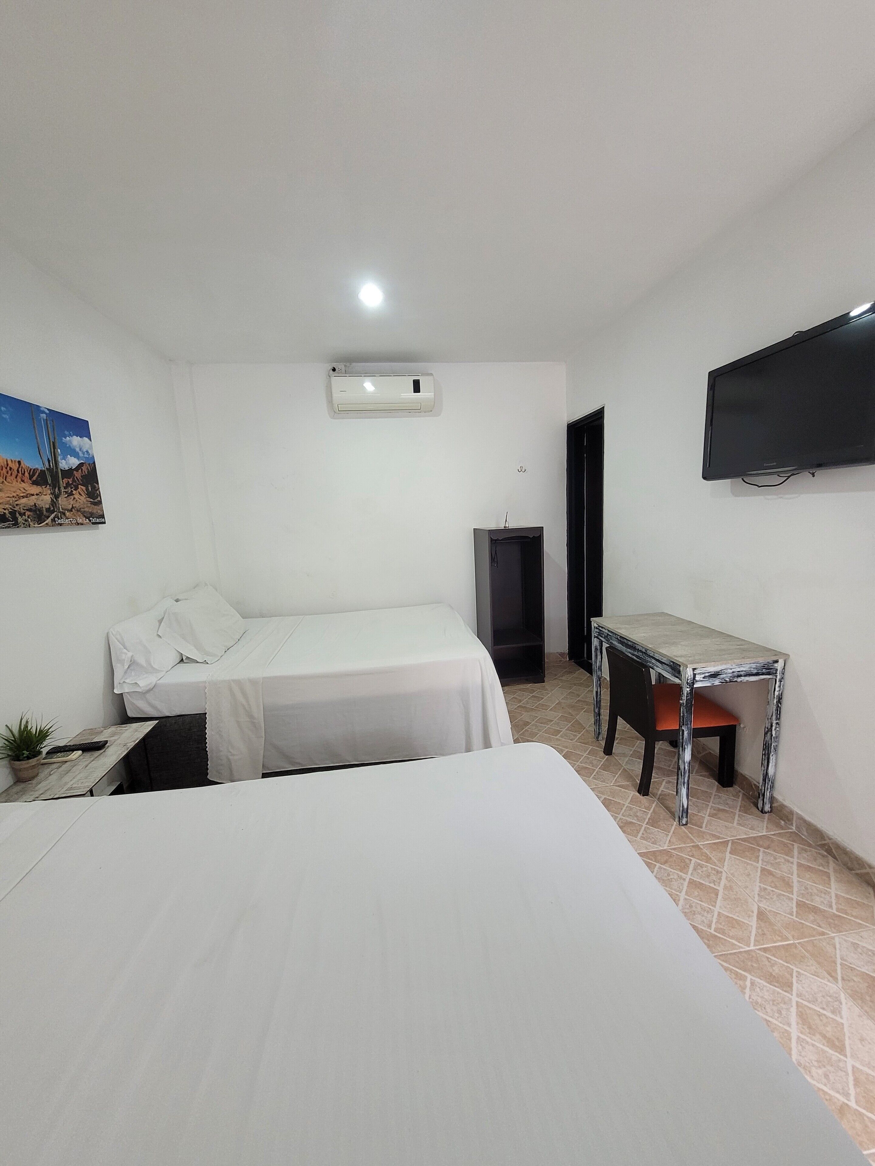 Une chambre à coucher avec un lit, un bureau, une chaise, une télévision et une porte.