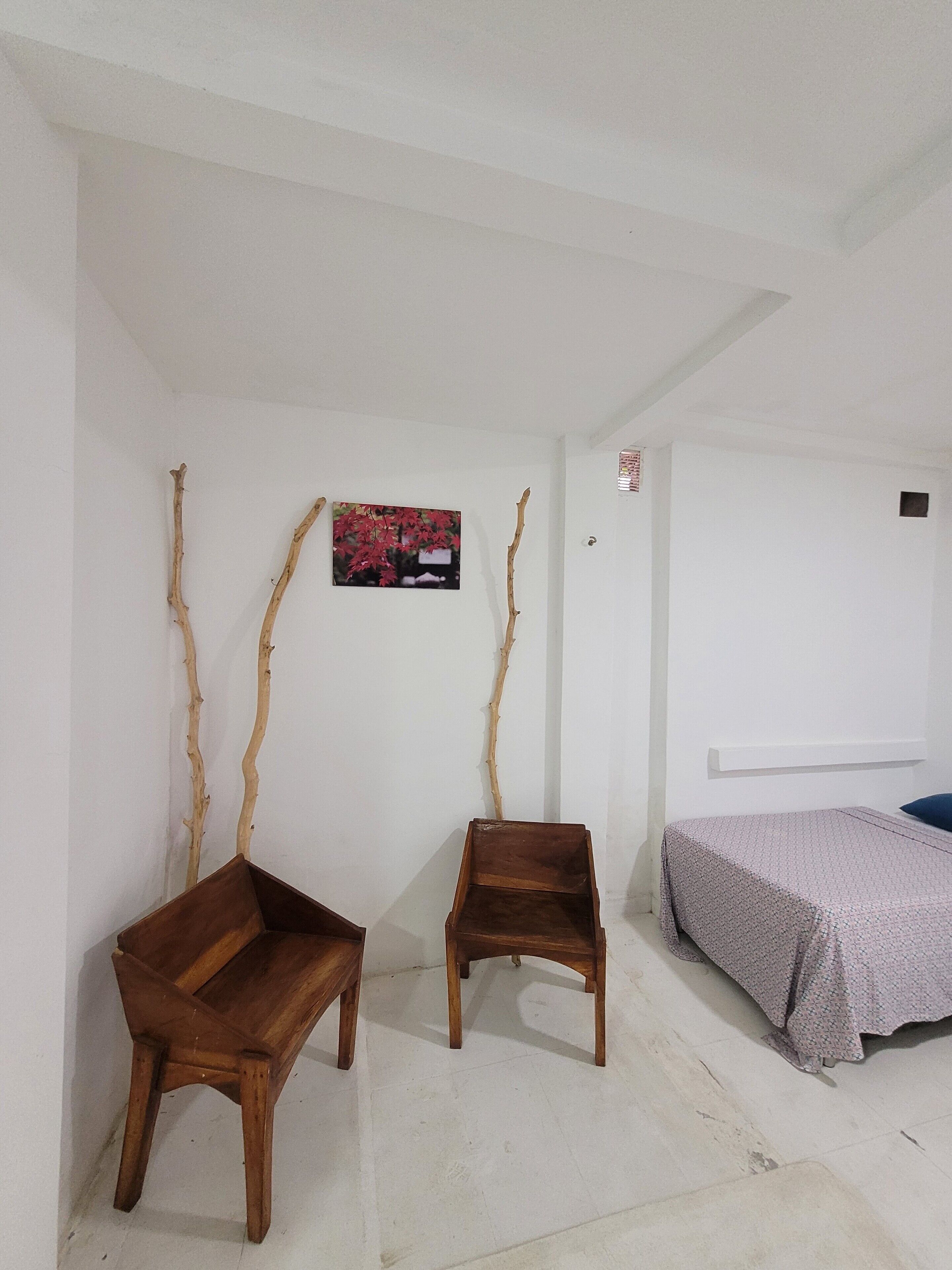 A room with two wooden benches, a bed with a patterned bedspread, and a wall-mounted picture.