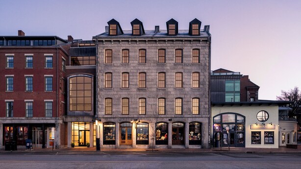 A multi-story building with a stone facade, large windows, and a corner entrance. - Evalina Hotel (Portland)