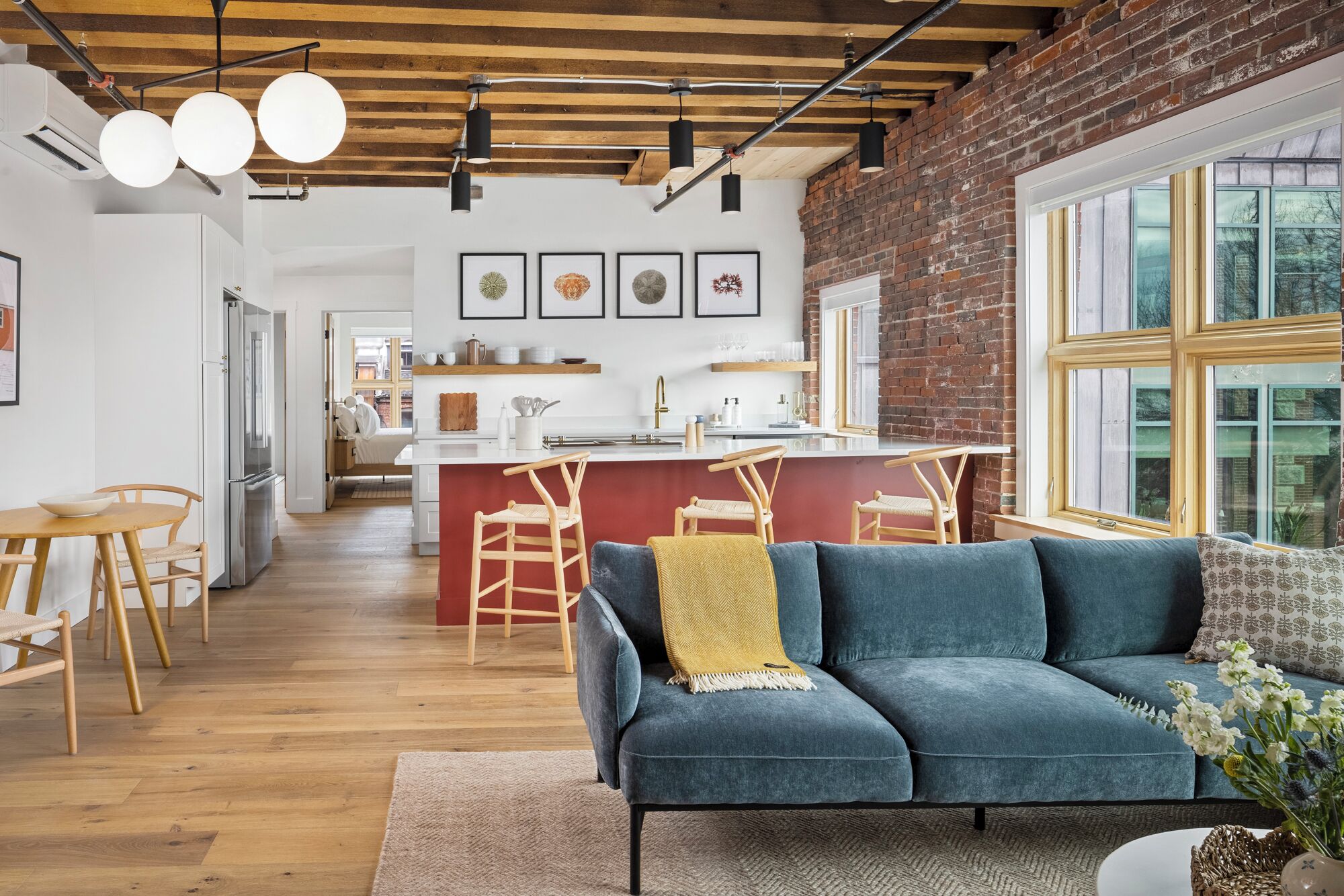 A modern interior with a sofa, dining area, kitchen, and large windows.