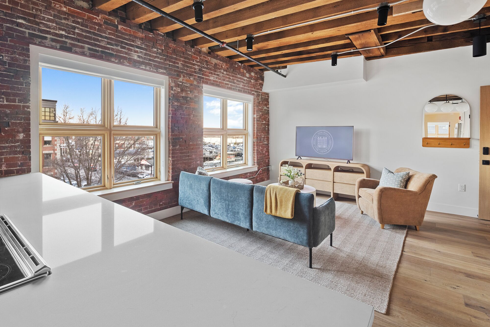 A modern living room with a large window, a sofa, a coffee table, and a TV.