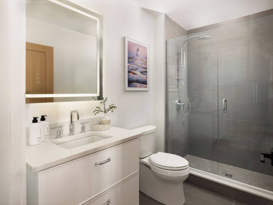 A modern bathroom with a glass-enclosed shower, a white sink, and a toilet.