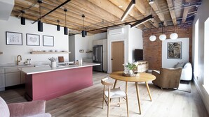 A modern kitchen with a central island, wooden beams on the ceiling, and a dining area with a round table and chairs. - Evalina Hotel (Portland)