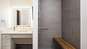 A modern bathroom with a shower, bench, and a vanity with a mirror and sink.