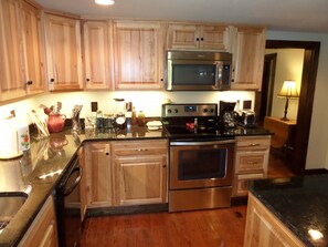 A kitchen with wooden cabinets, stainless steel appliances, and a granite countertop. - Remote | historic cabin | renovated | Fire pit. (Rogers)