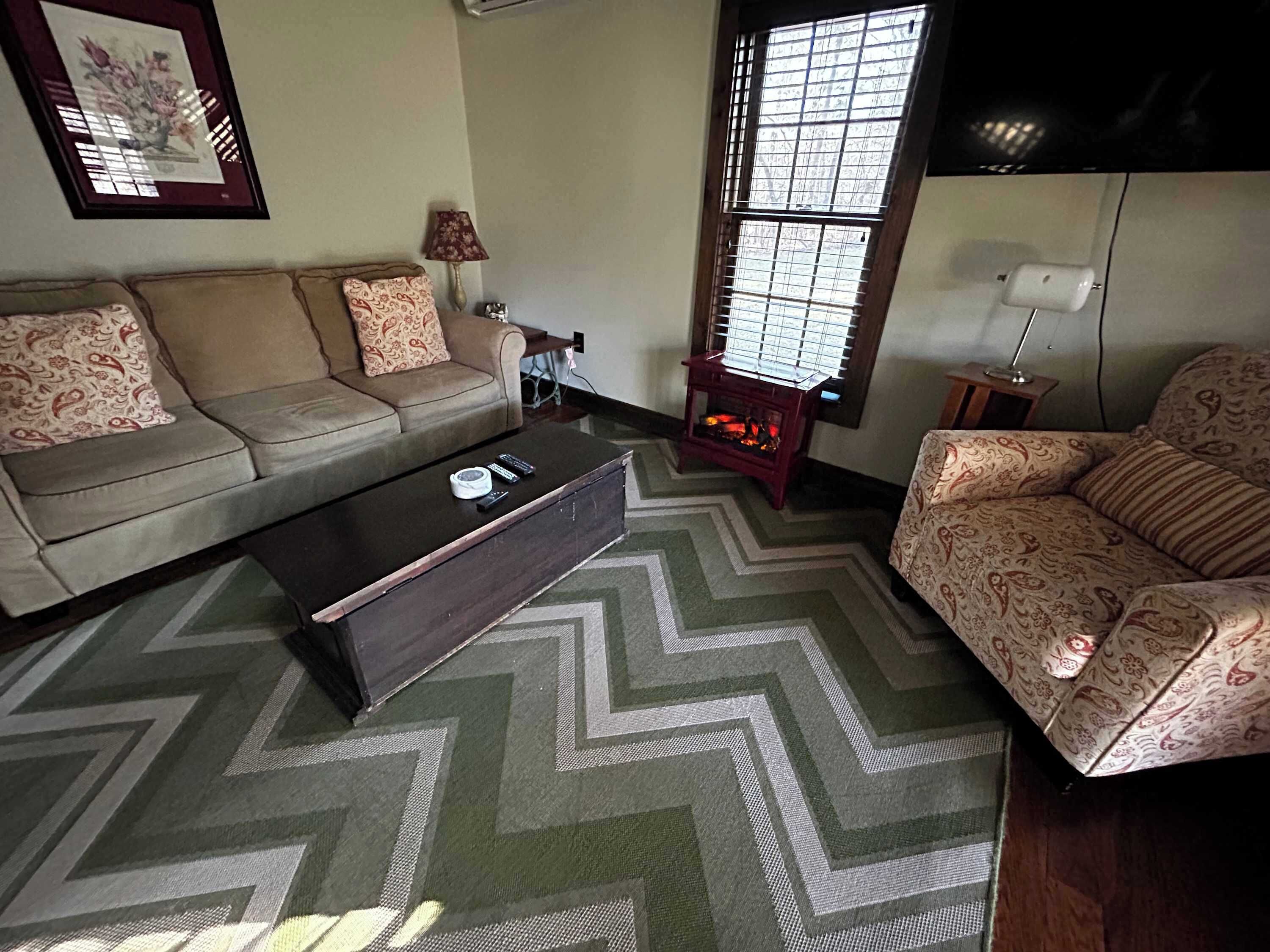 A living room with a sofa, a coffee table, and a patterned rug.