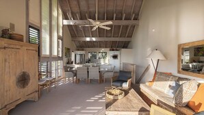 A spacious living area with a high ceiling, wooden furniture, and a dining area with a kitchen in the background. - 2 Story Ocean-View 2BR, 2 Lanais, Vaulted Ceilings, Resort Pool -Unit 23 (Koloa)