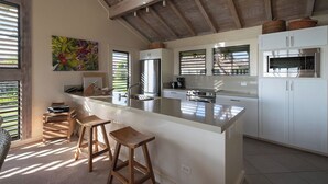 A modern kitchen with a large island, white cabinetry, and a wooden ceiling. - 2 Story Ocean-View 2BR, 2 Lanais, Vaulted Ceilings, Resort Pool -Unit 23 (Koloa)