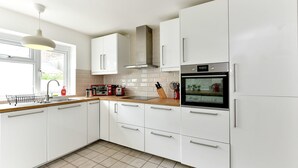 Una cocina moderna con armarios blancos, un horno de acero inoxidable y un ventanal que proporciona luz natural.