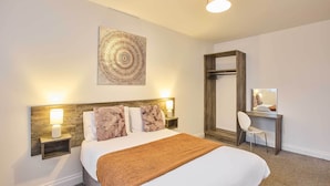 Une chambre d’hôtel bien aménagée, avec un grand lit, un bureau et un miroir.