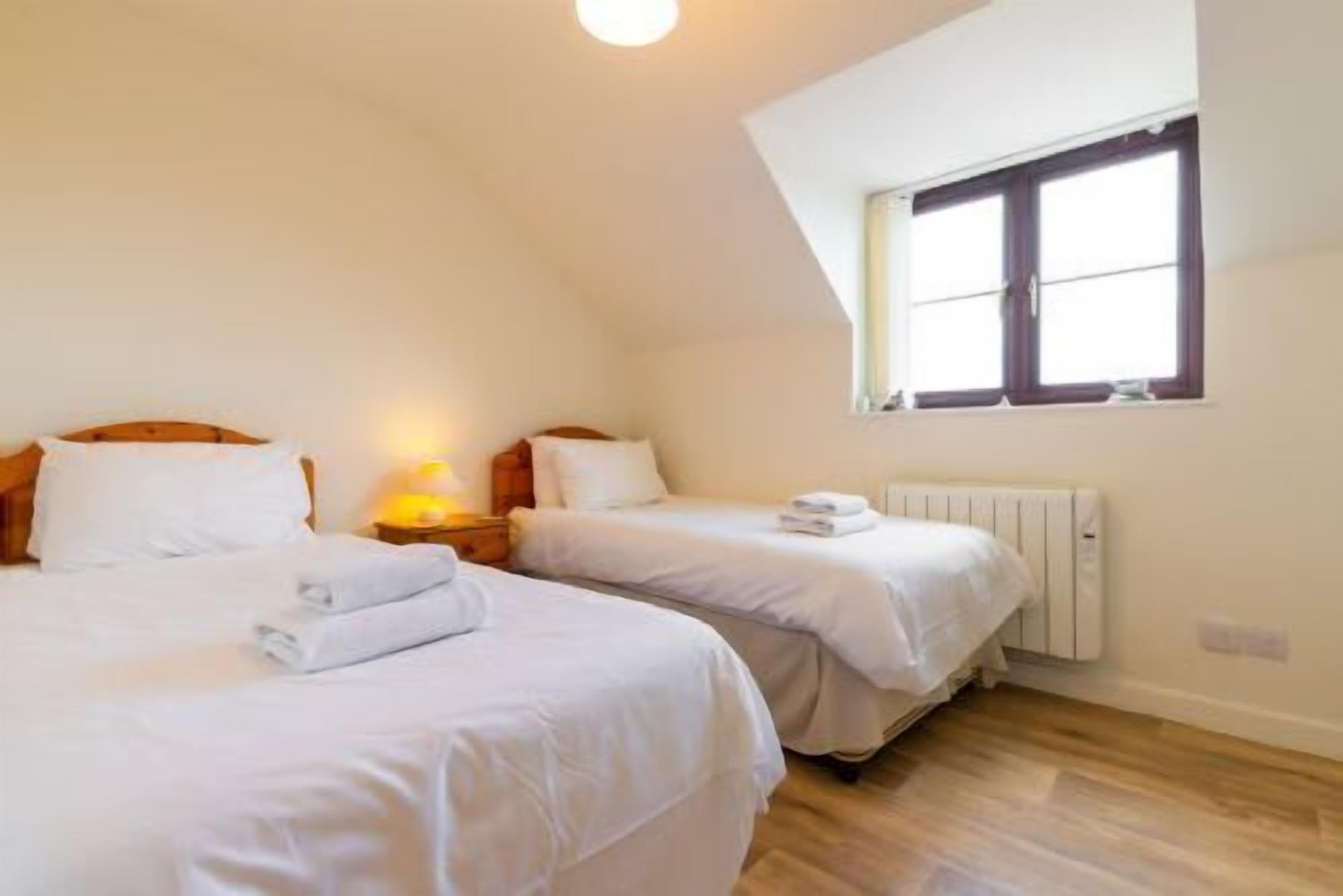 Een slaapkamer met twee bedden, een raam en een radiator.