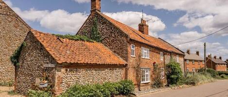 A traditional stone and brick house with a tiled roof, a visible chimney, and a sign reading "Chapel Yard".