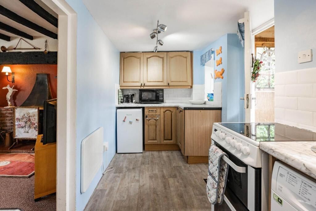 A compact kitchen with wooden cabinets, a microwave, a refrigerator, and a stove.