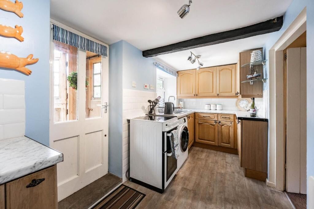 Une cuisine compacte avec des meubles en bois, un lave-linge encastré et un plan de travail en marbre.
