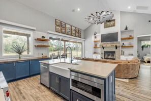 Una cocina moderna con una isla grande, electrodomésticos integrados y un área de comedor con un sofá de cuero marrón.