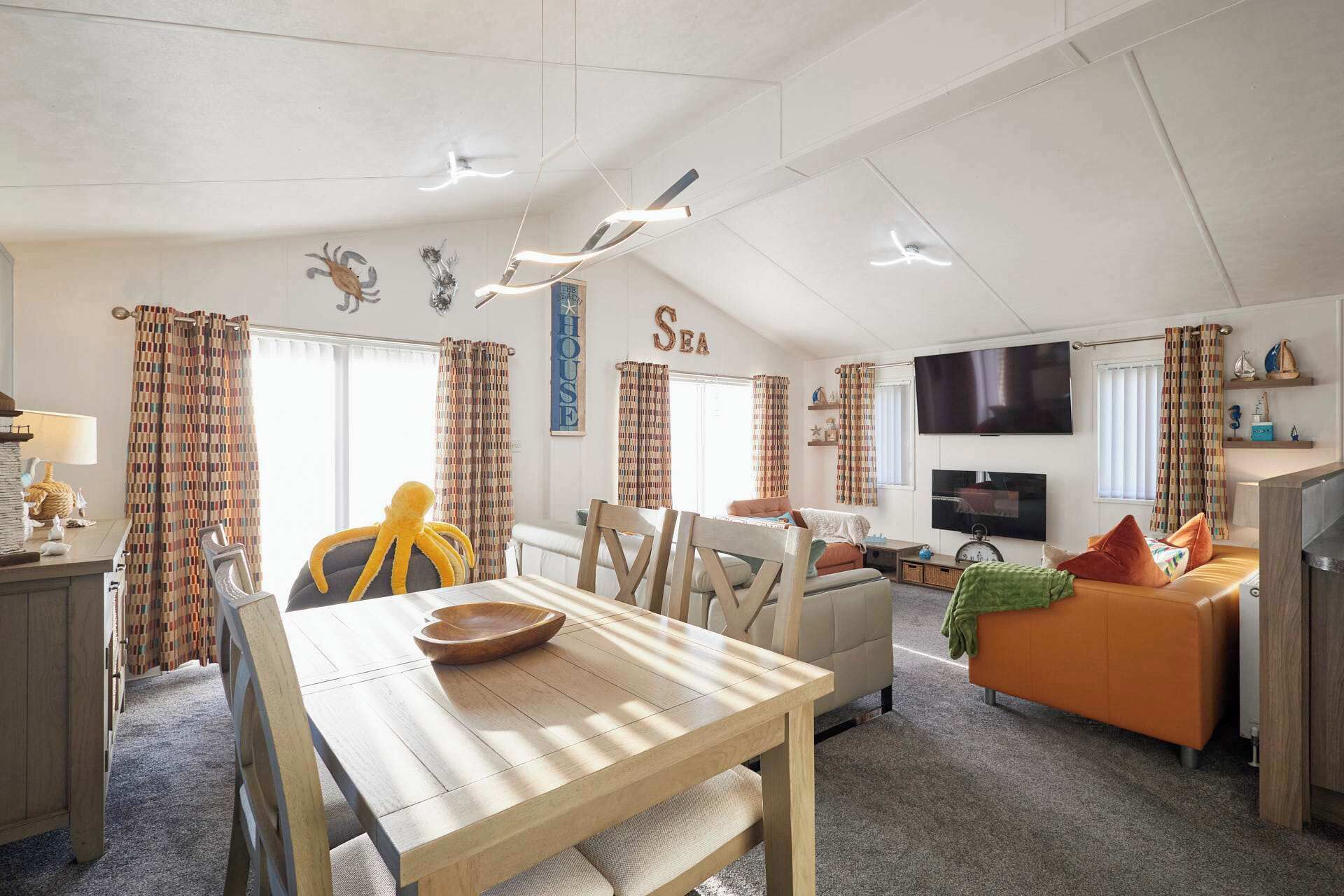 Ein geräumiges Wohnzimmer mit Essbereich, Fernseher und einer Couch.