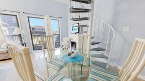 Ein modernes Wohnzimmer mit Glastisch, gestreiften Stühlen, einer Wendeltreppe und Blick ins Freie.