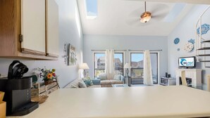 Eine moderne Küche mit Geschirrspüler, Kaffeemaschine und einem Essbereich mit Sofa und Tisch.