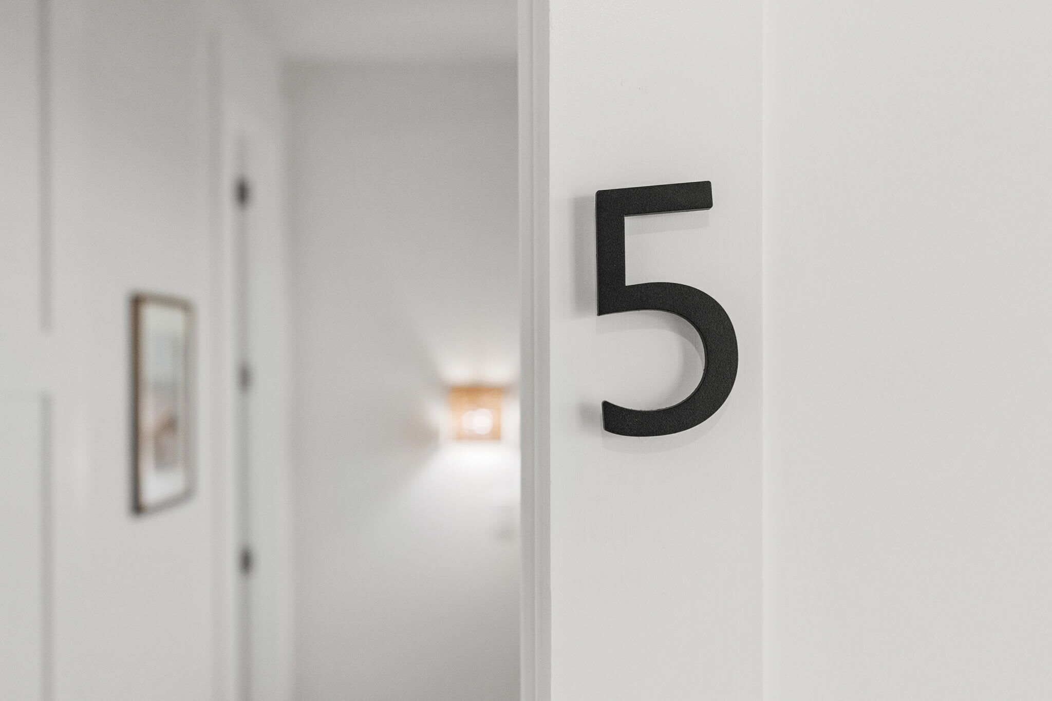 A hallway with a white door and a black number '5' sign.