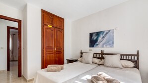 Un dormitorio con una cama, un armario de madera y un cuadro en la pared.