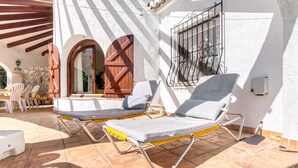 Un patio con dos sillones, una puerta de madera y una ventana con rejas.