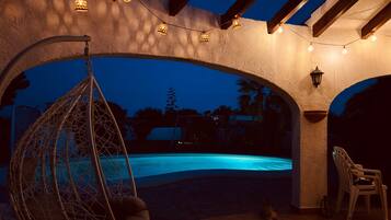 Un área de piscina con una hamaca colgante, una silla y luces de cuerda.