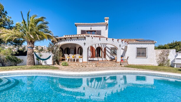 Una villa junto a la piscina con una piscina cristalina, un patio con muebles de exterior y vistas del entorno.