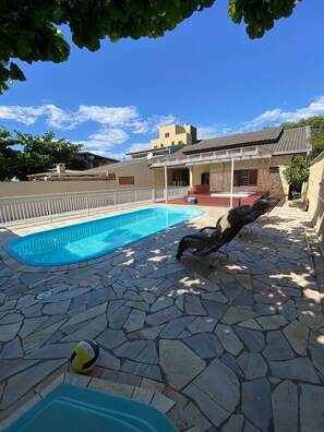 A swimming pool with a stone deck, a lounge chair, and a volleyball. - Spacious house with a heated hot tub and pool on Shangri-La Beach. (Pontal do Paraná)