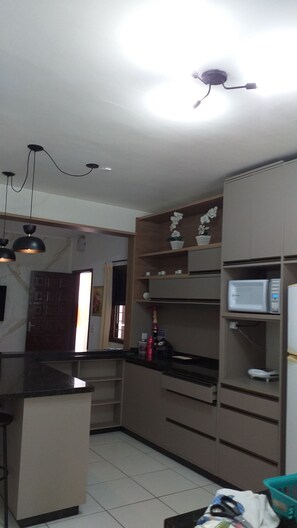 A kitchen with a central island, built-in microwave, and a ceiling light fixture.