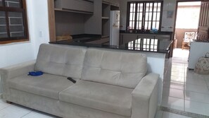 A beige sofa in a room with a kitchen area visible in the background.