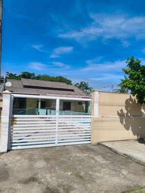 A gated residential property with a metal gate, a concrete driveway, and a clear blue sky. - Spacious house with a heated hot tub and pool on Shangri-La Beach. (Pontal do Paraná)