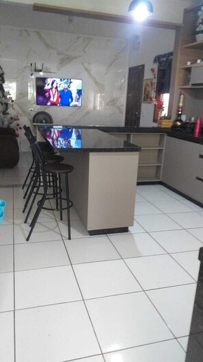 A kitchen with a central island, bar stools, and a television mounted on the wall.