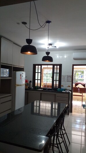A kitchen with a central island, pendant lighting, and a view through a window.