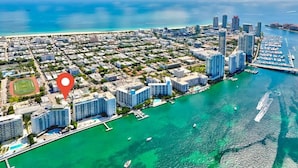An aerial view of a coastal city with high-rise buildings, a marina, and a clear blue sea. - 1BR Miami Beach Apt w/ King + 2 Queens & Smart TV (Miami Beach)