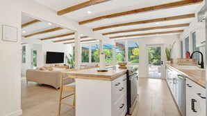 A modern kitchen with wooden beams, a central island, and a dining area with a view. - Casa in Tropic Paradise with Pool and BBQ (Biscayne Park)
