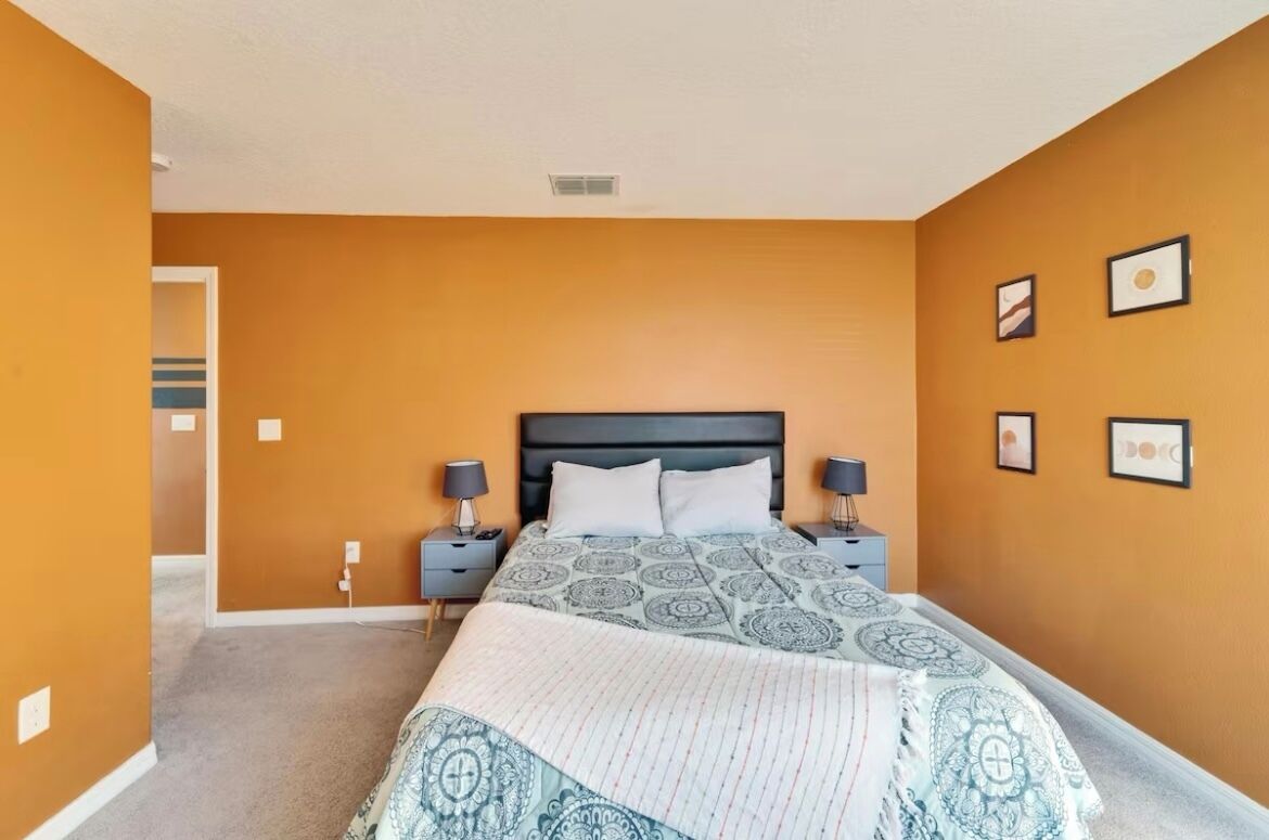 Une chambre à coucher avec un lit, deux tables de chevet et une porte donnant sur une autre pièce.